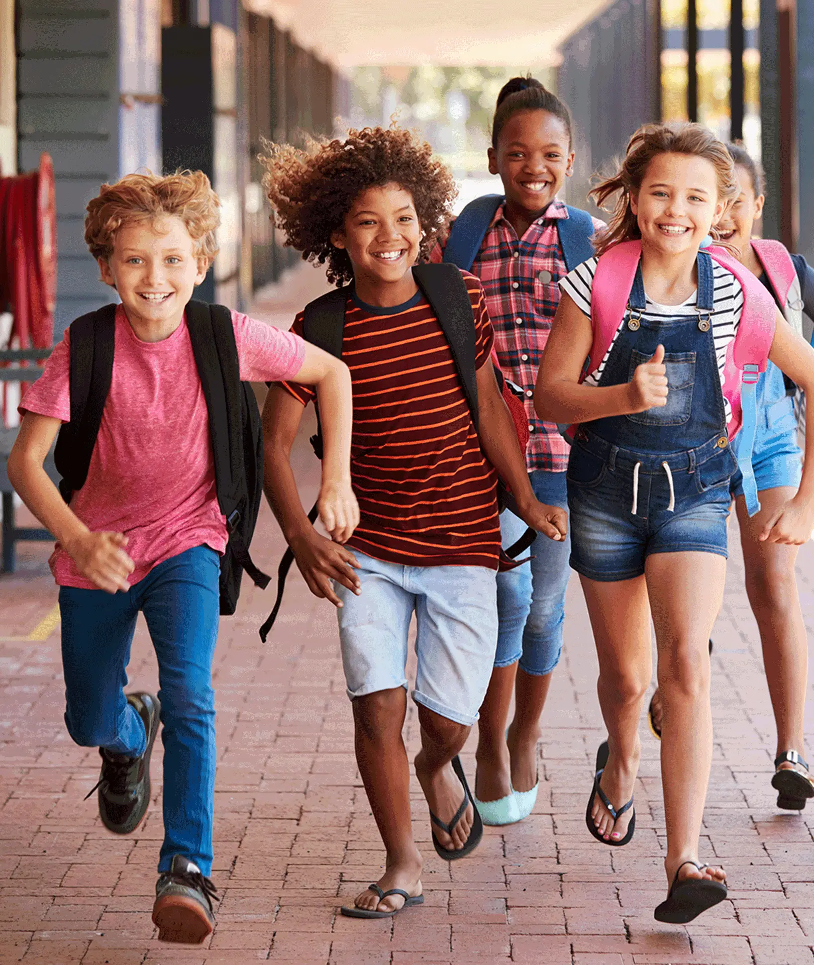 Children carrying backpacks walking together outside a school