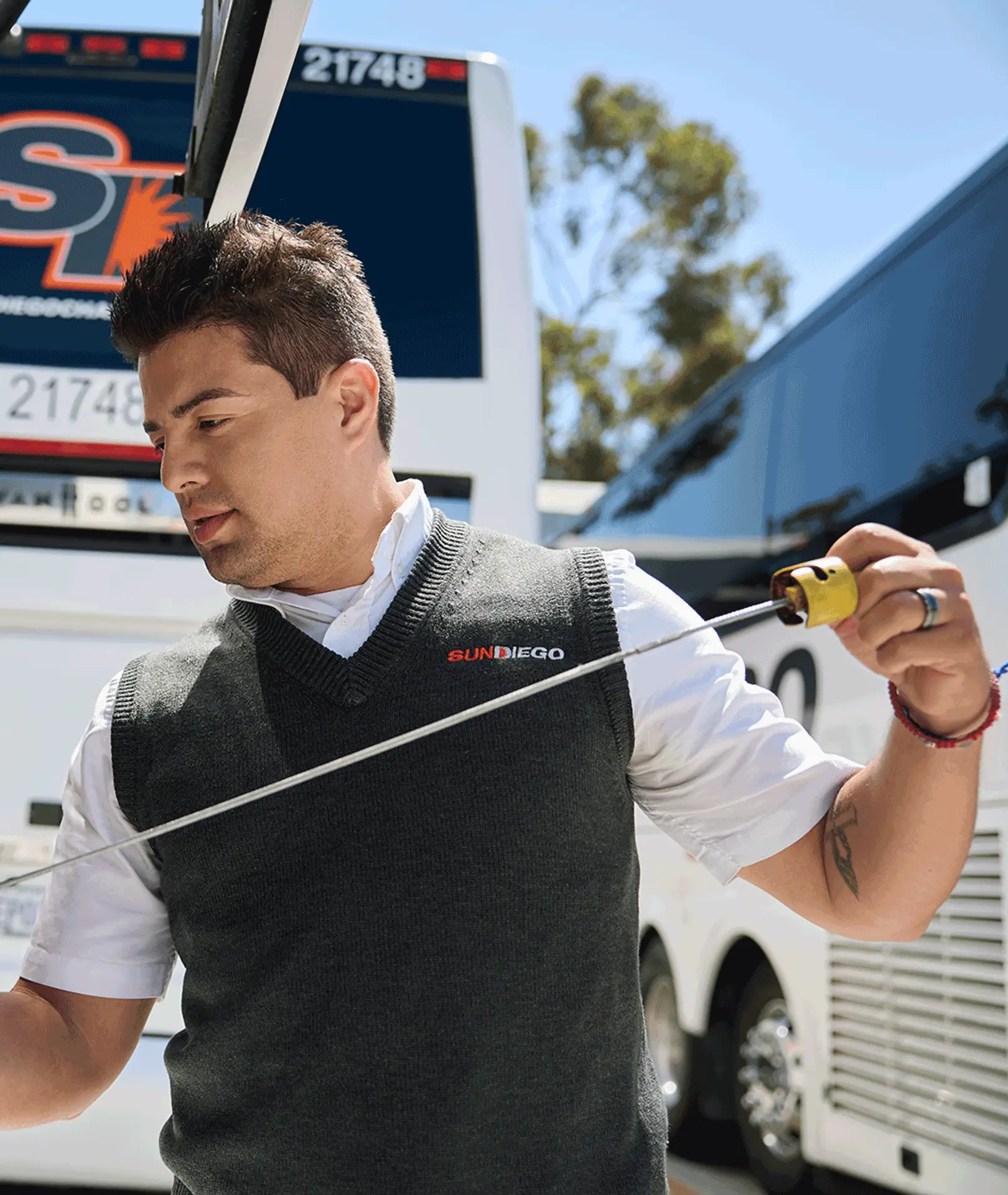 Sun Diego Charter team member checking a motorcoach engine dipstick