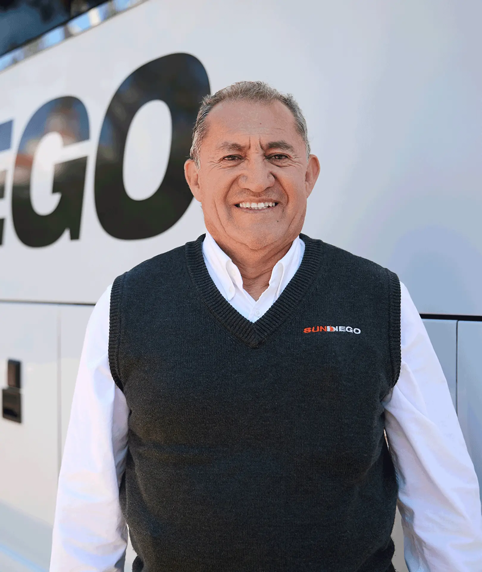Smiling Sun Diego Charter team member standing beside a motorcoach