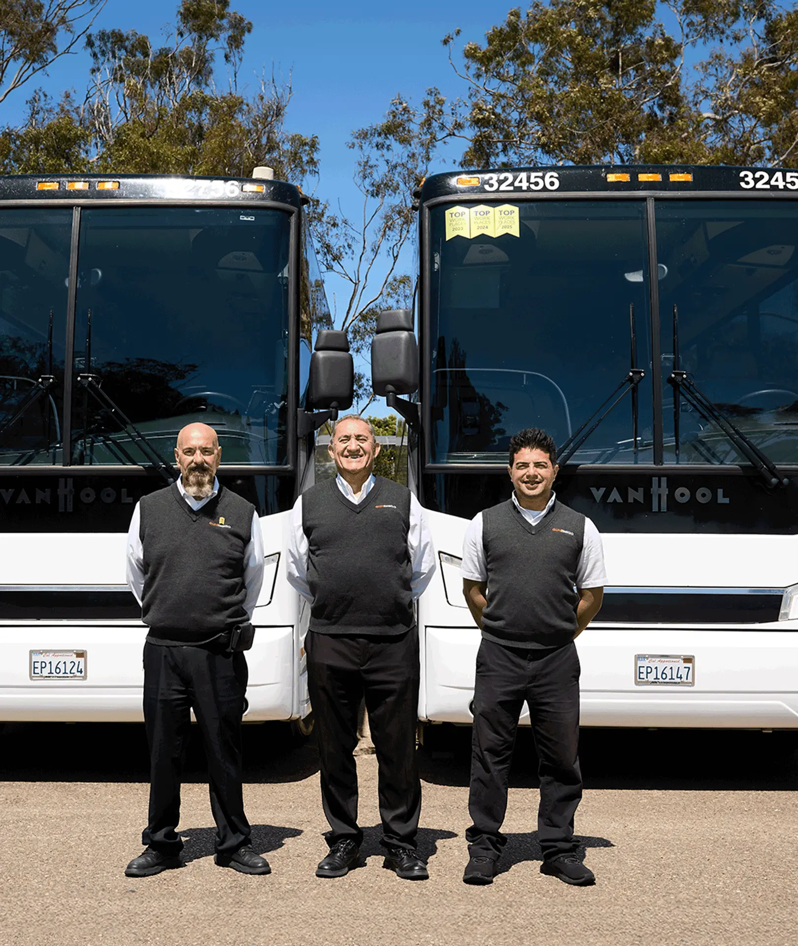 Three uniformed Sun Diego Charter team members standing in front of motorcoaches
