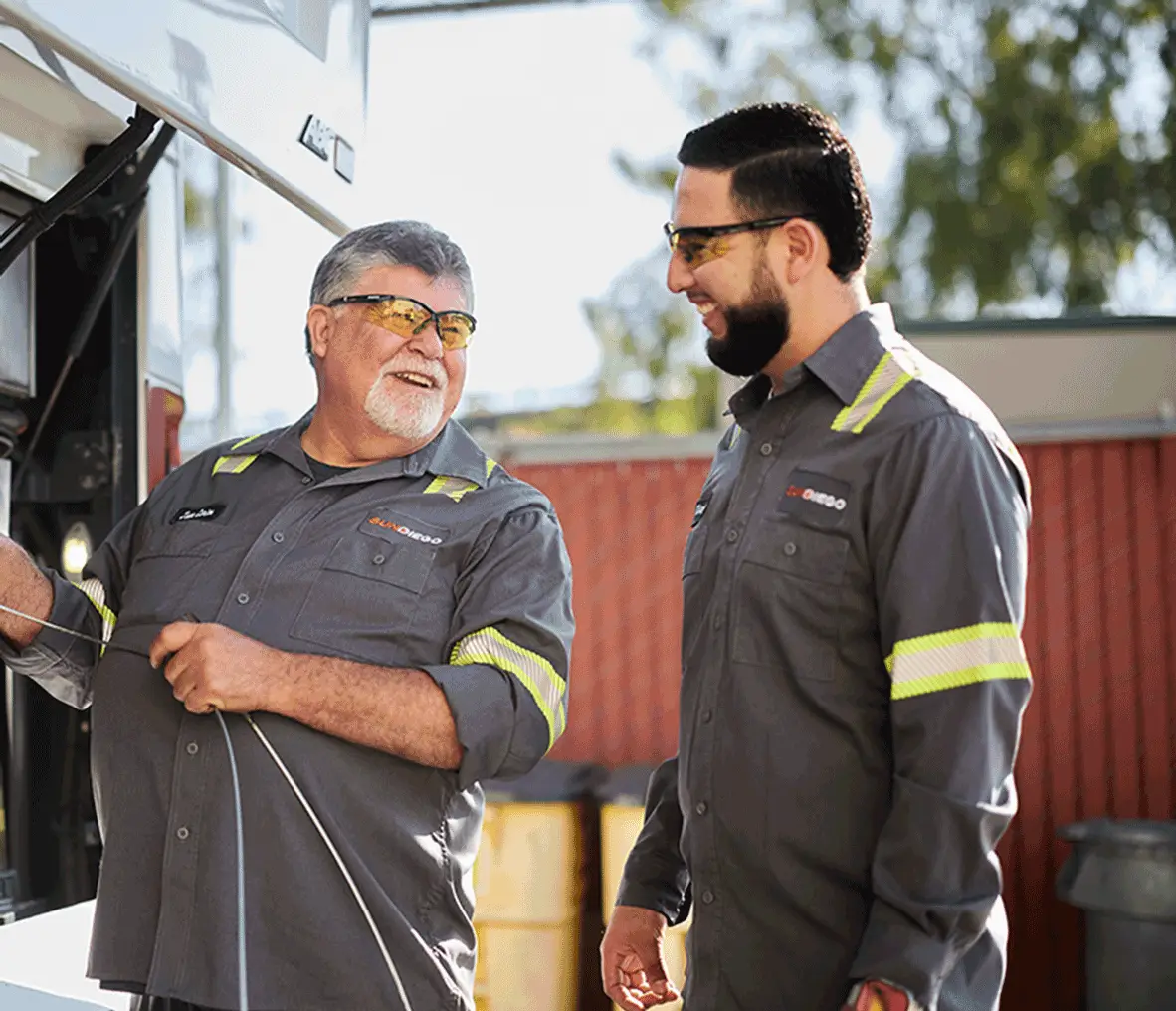 Two maintenance technicians beside an open motorcoach engine compartment