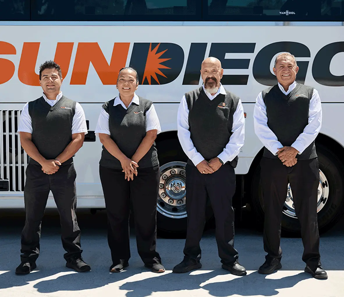 Four uniformed Sun Diego Charter team members standing beside a motorcoach