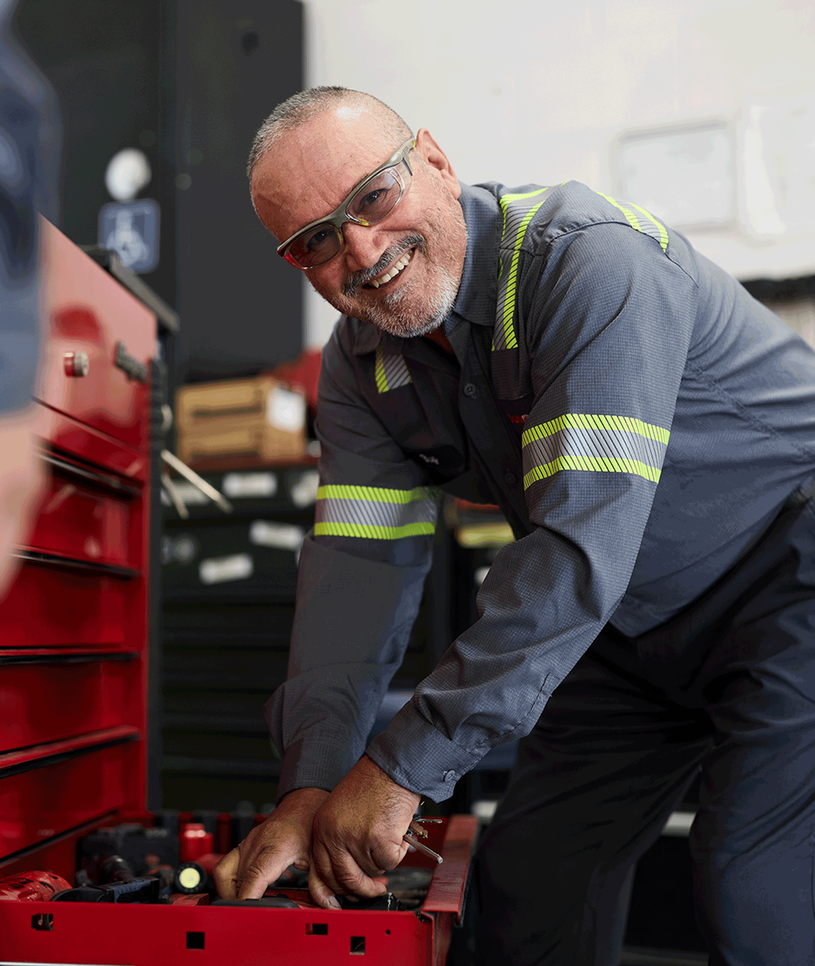 Smiling maintenance technician leaning over a toolbox