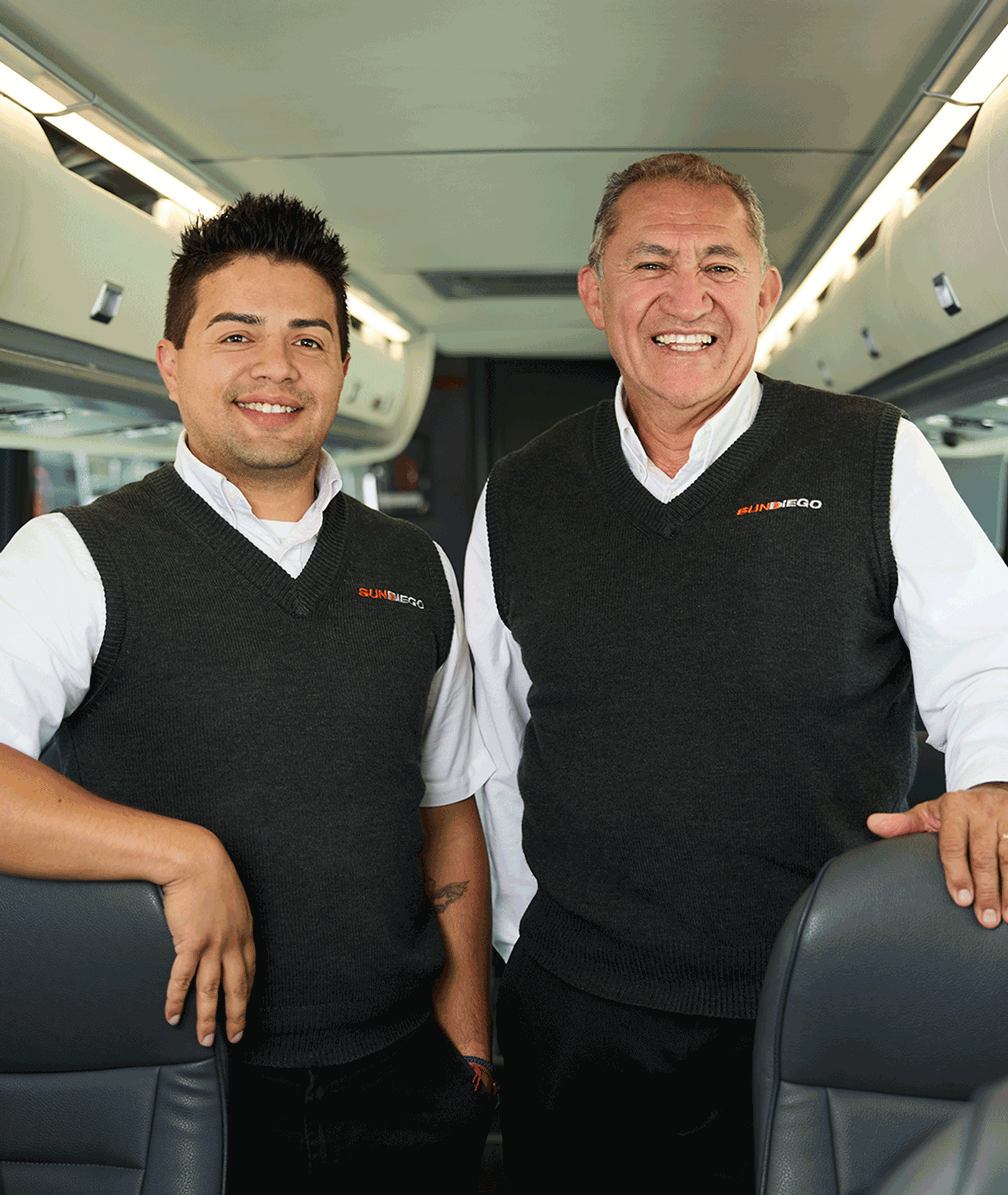 Two smiling Sun Diego Charter team members inside a motorcoach