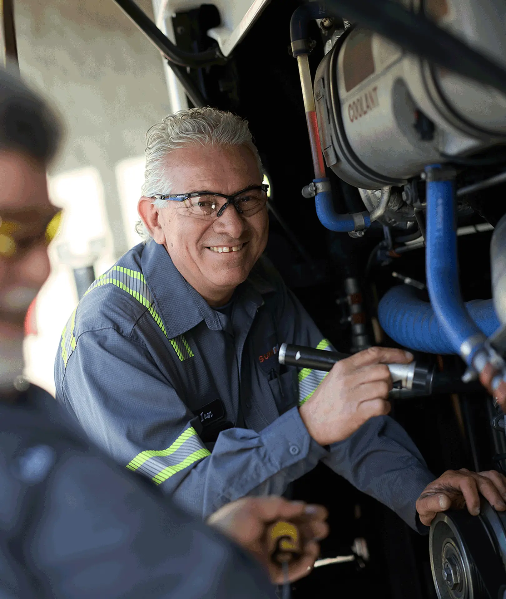 Maintenance technician using a flashlight to inspect a motorcoach engine