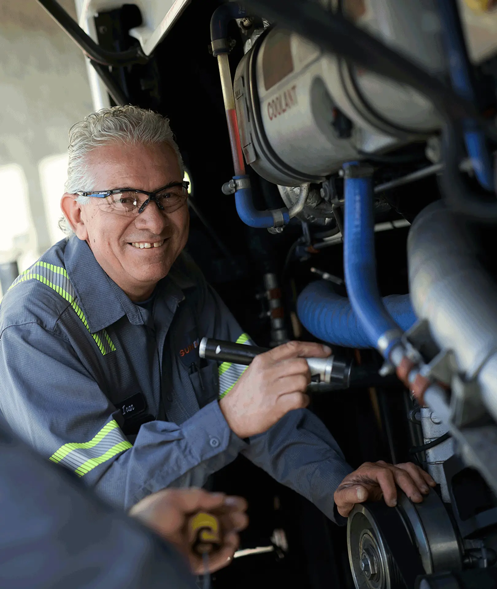 Maintenance technician using a flashlight to inspect a motorcoach engine