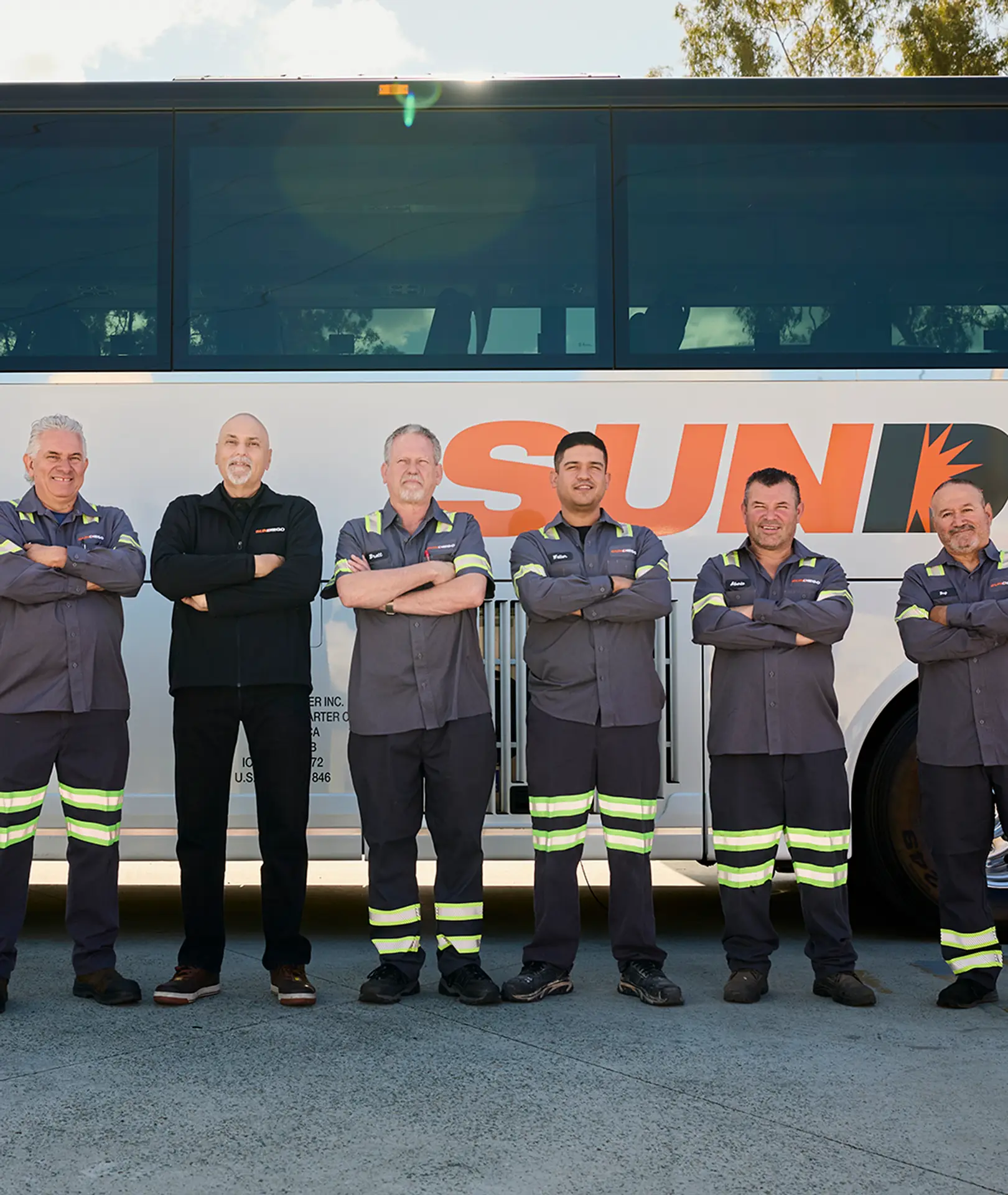Sun Diego Charter maintenance team standing beside a motorcoach