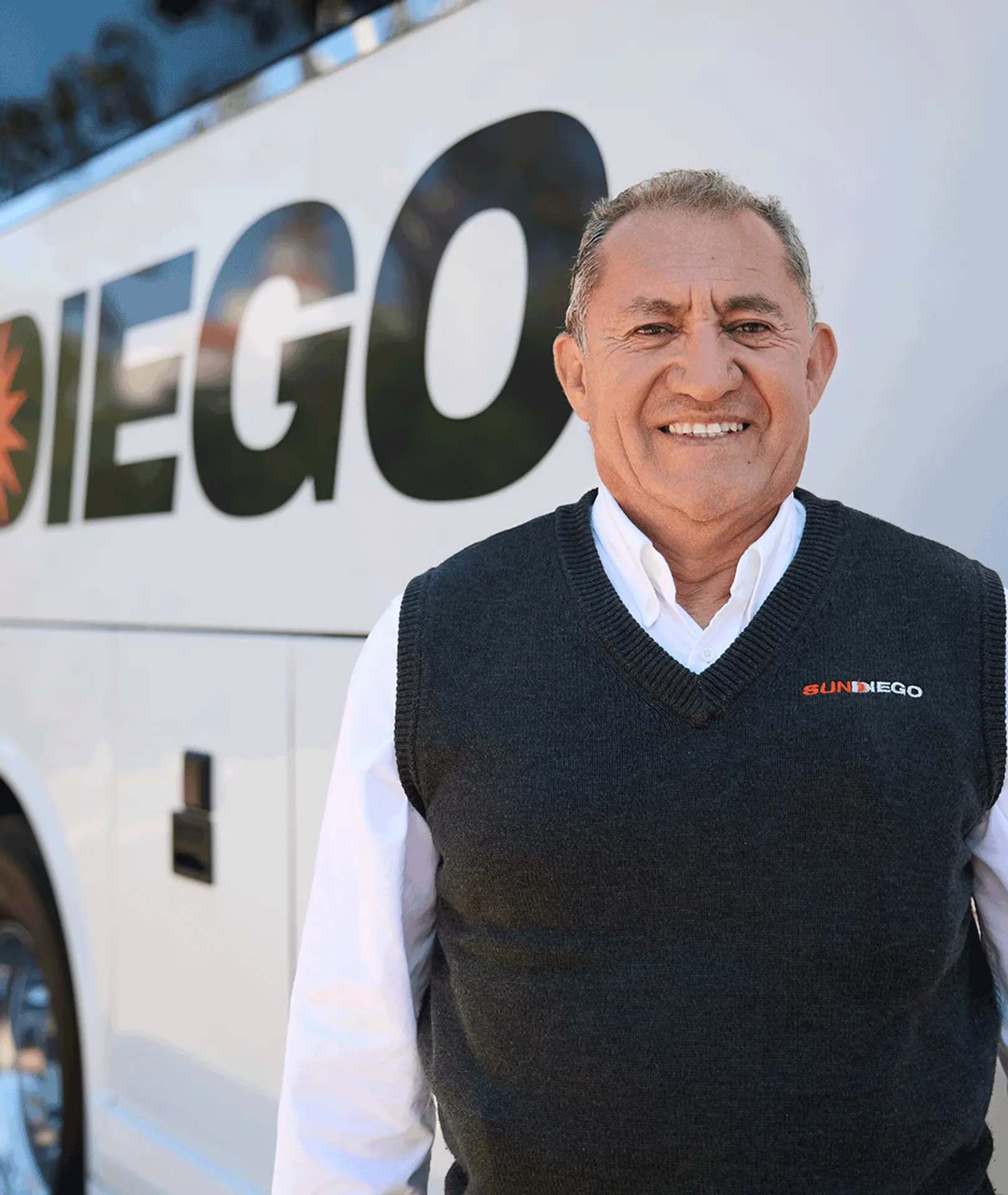 Smiling Sun Diego Charter team member standing beside a motorcoach