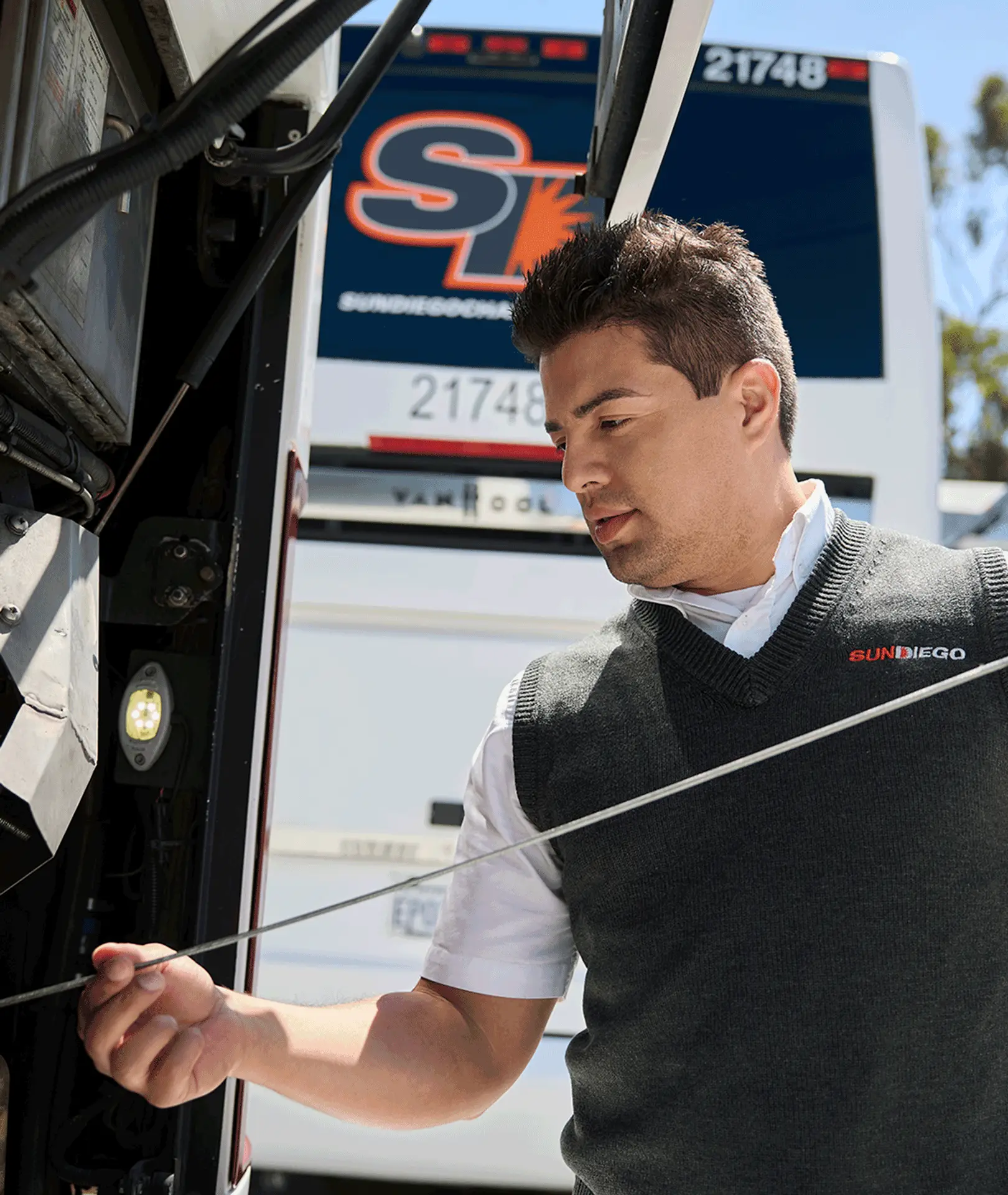 Sun Diego Charter team member checking a motorcoach engine dipstick
