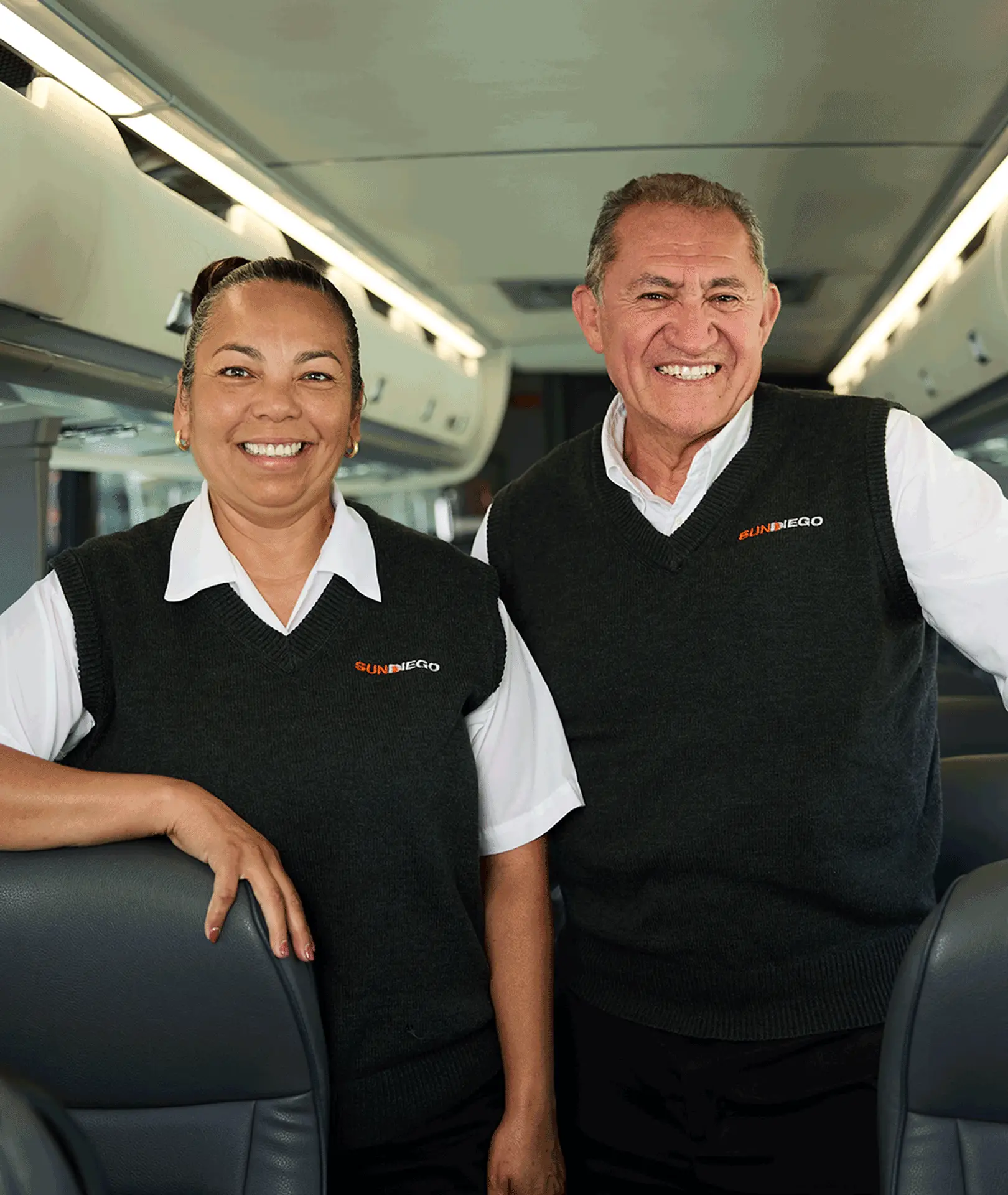 Two smiling Sun Diego Charter team members inside a motorcoach