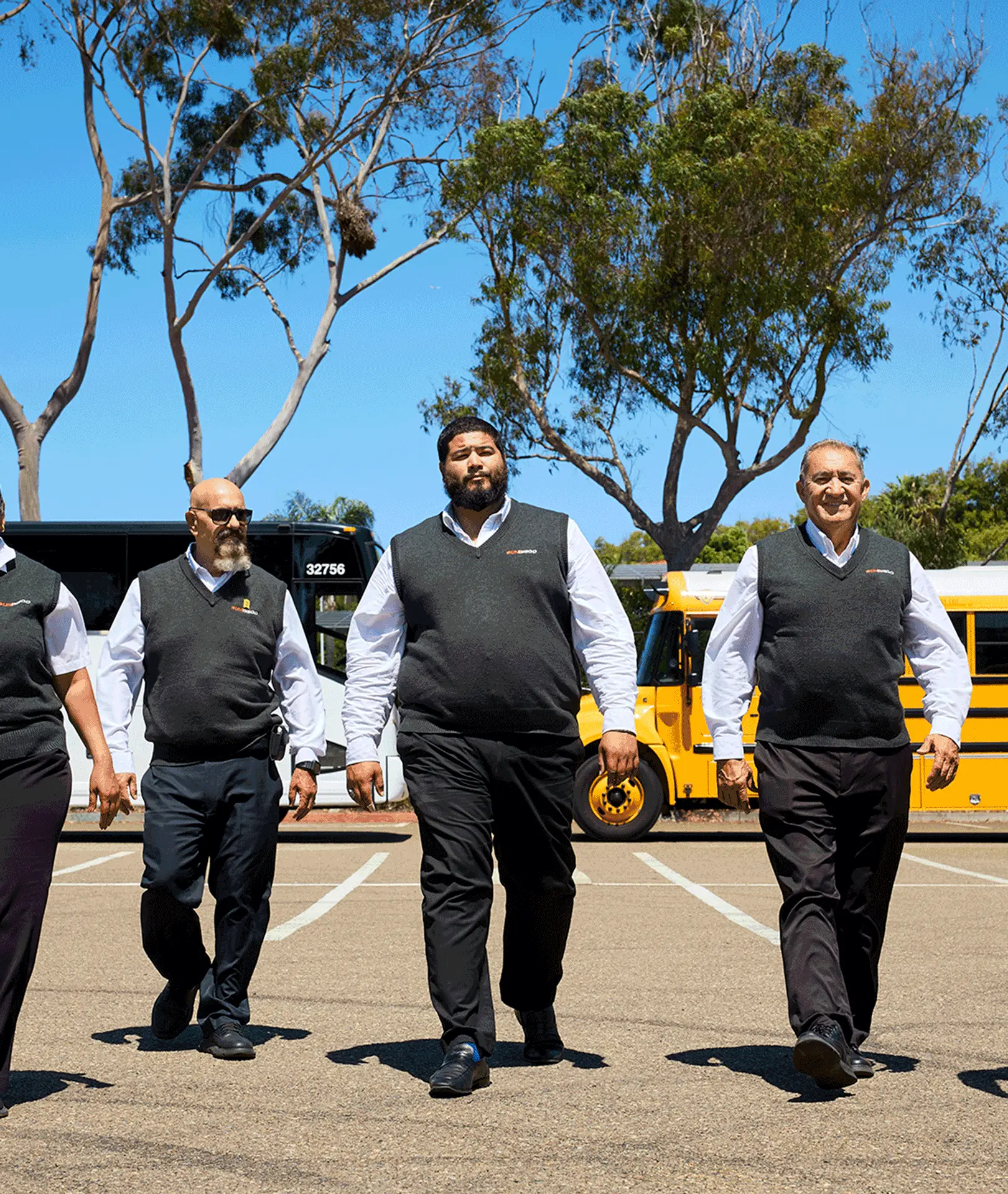 Uniformed Sun Diego Charter team members walking through the vehicle yard