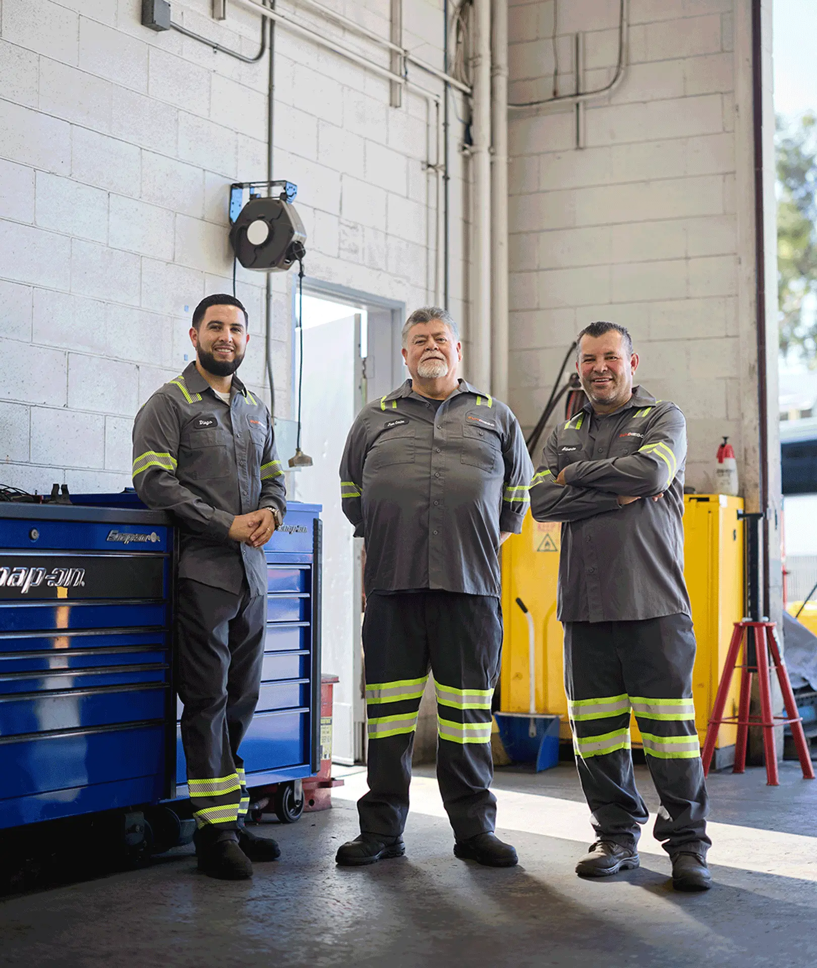 Three maintenance team members standing inside a vehicle workshop