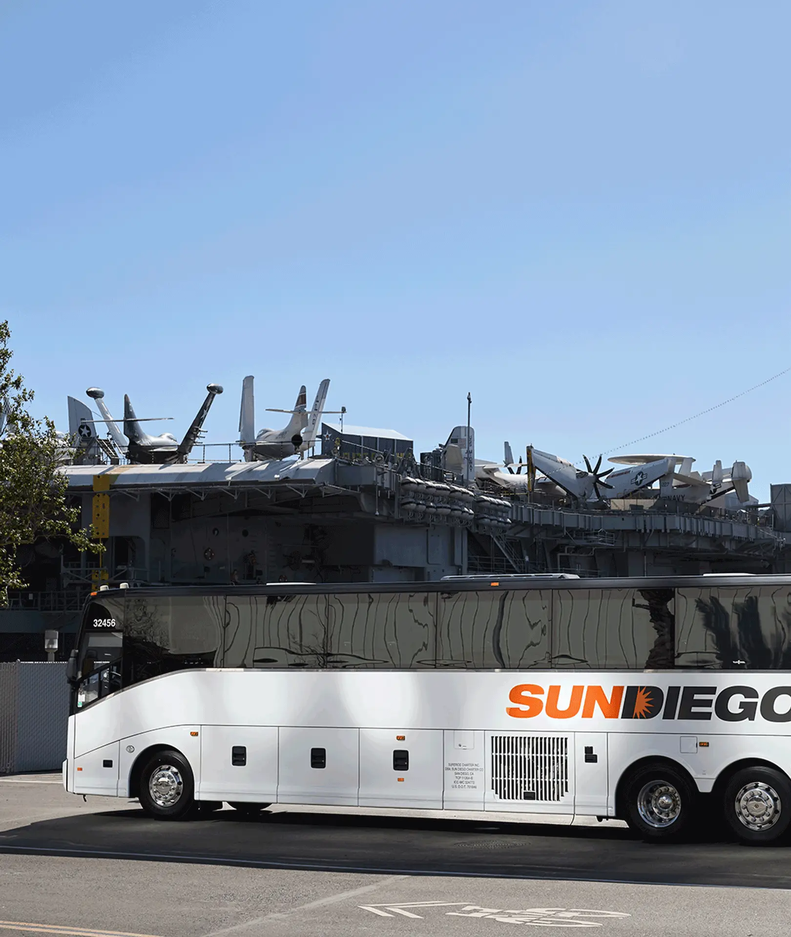Sun Diego Charter motorcoach parked beside a waterfront ship