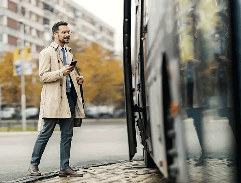 Traveler holding a phone beside a motorcoach
