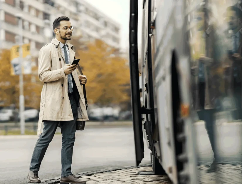 Traveler holding a phone beside a motorcoach